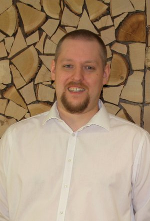 Kundendiensttechniker Florian März vor einer Holzwand
